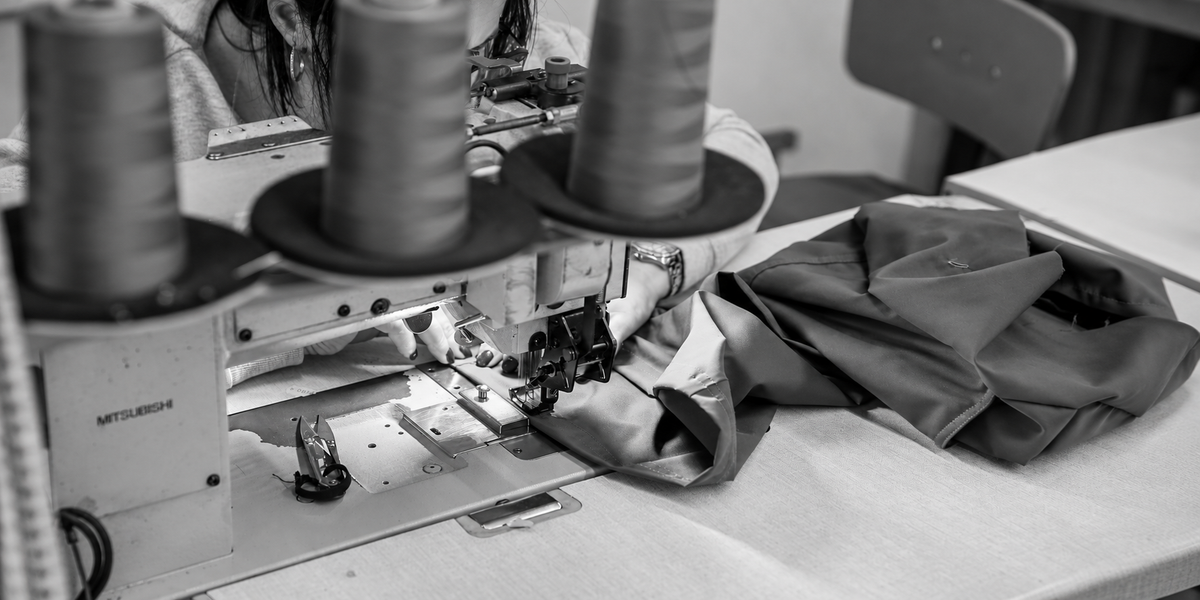 Close-up van een naaimachine met grijze zwembroekstof in het productieatelier in Porto